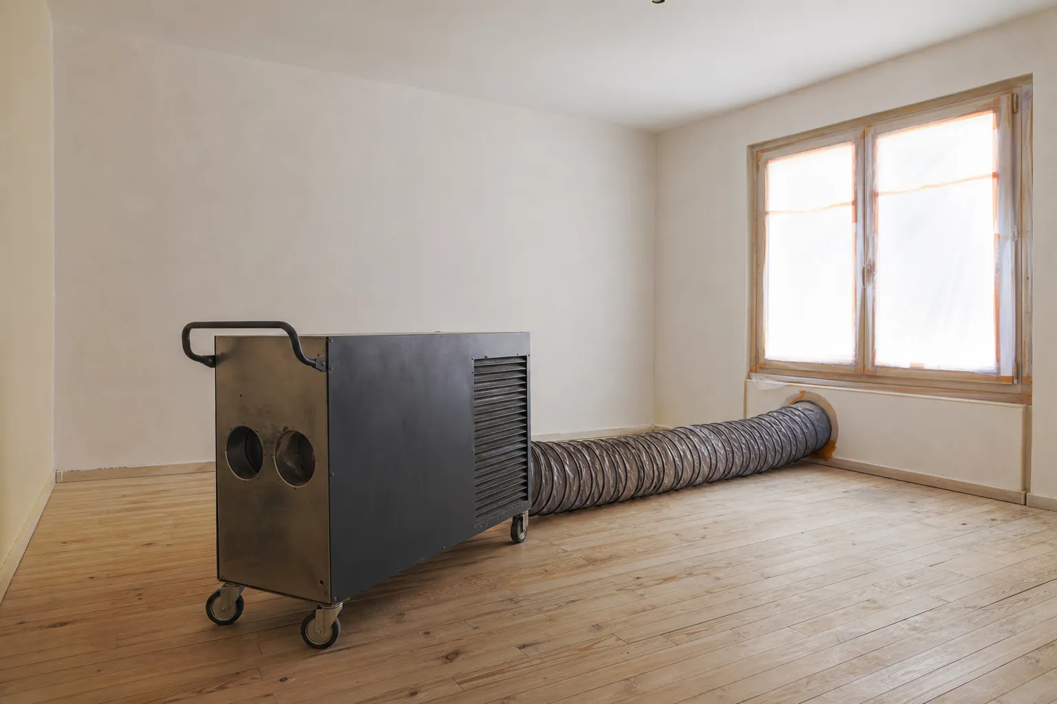 Générateur d'air chaud professionnel et sa gaine souple installés au centre d'une chambre entièrement vidée